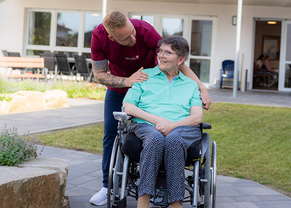 Person im Rollstuhl mit Pflegekraft